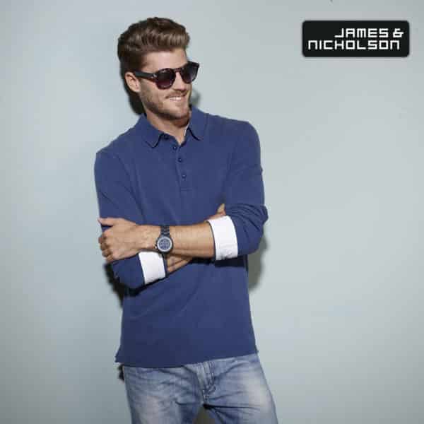 Ragazzo con barba occhiali braccia conserte con polo manica lunga blu navy con inserti e jeans