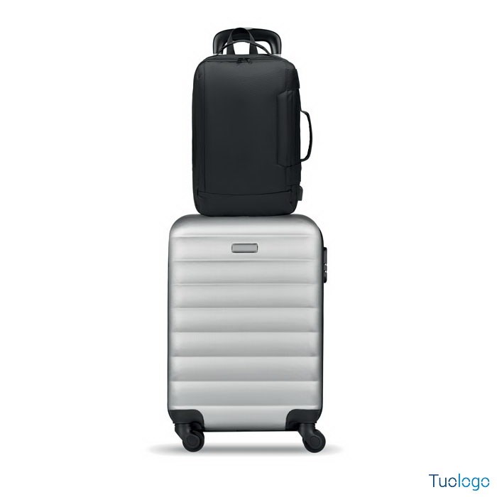 Zaino nero sopra valigia grigia su sfondo bianco