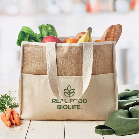 Shopper in juta con manici lunghi e tasca frontale con logo su un tavolo