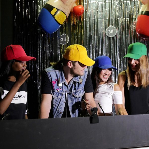 Tre ragazze e un ragazzo che indossano cappellini colorati a un bancone con gonfiabili