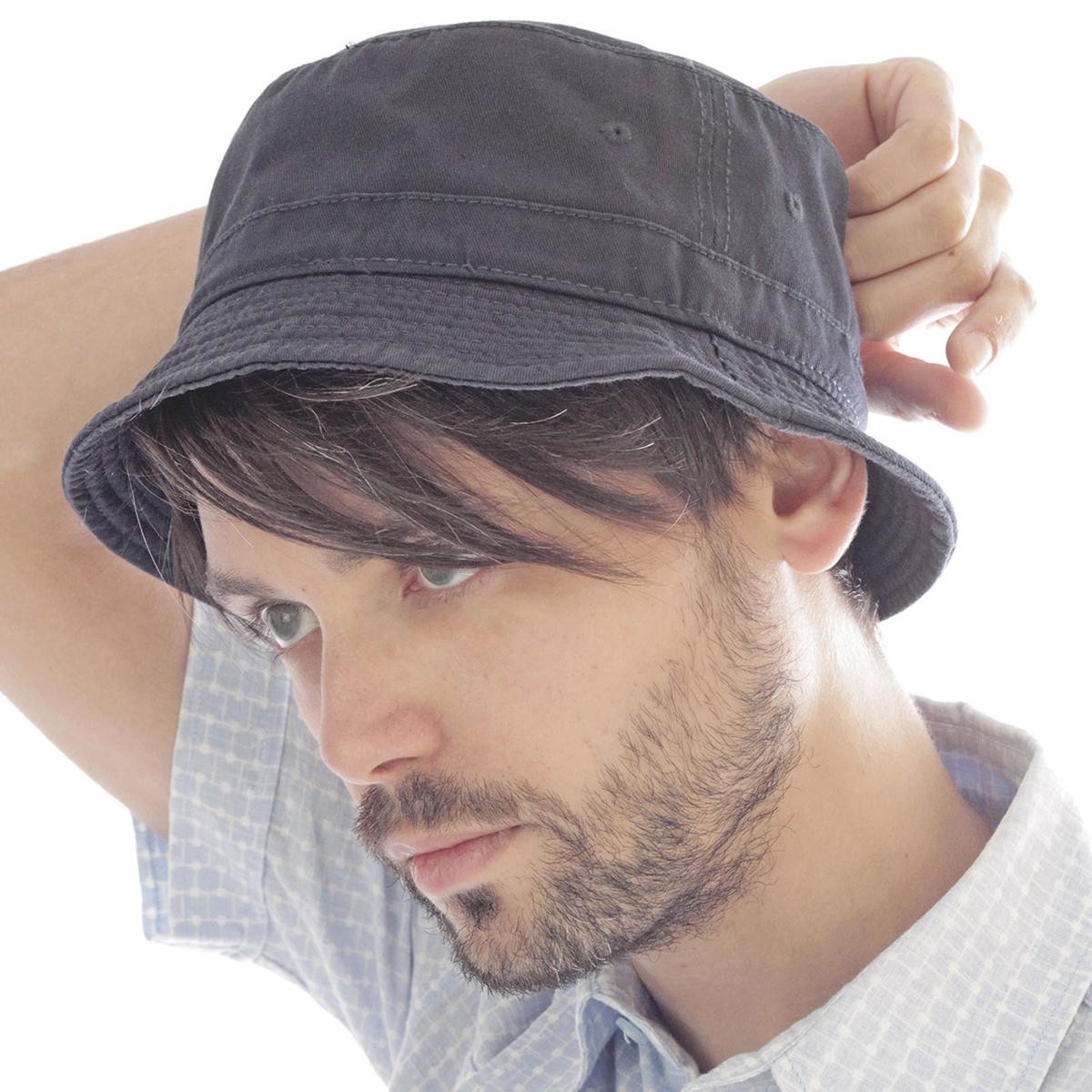 Ragazzo castano con barba con camicia fantasia che indossa cappellino pescatore blu