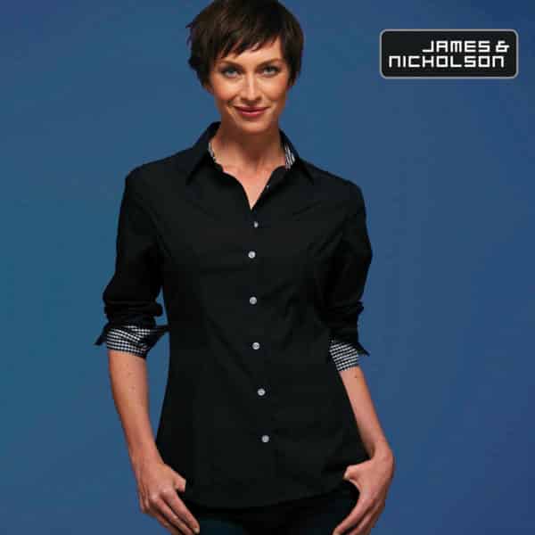 Donna con capelli corti e camicia nera manica lunga e dettagli a quadretti su sfondo blu