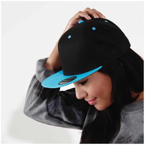 Ragazza di profilo con lunghi capelli neri e cappellino nero con dettagli azzurri