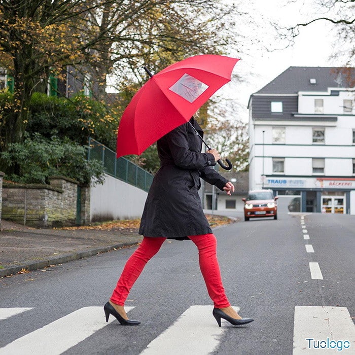 Donna  che attraversa la strada con ombrello automatico in poliestere arancione, con manico in plastica e finestra trasparente