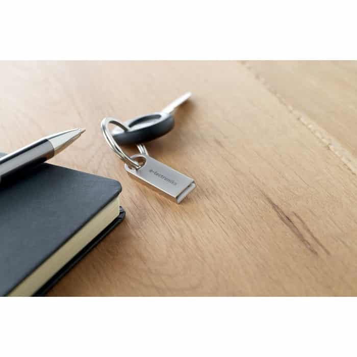 Mini chiavetta usb in alluminio con dettagli rotondi su un tavolo usata come portachiavi