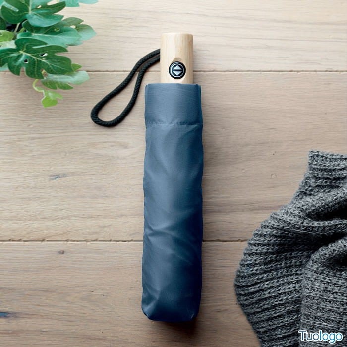 Ombrello viola chiuso dentro custodia, sopra tavolo di legno