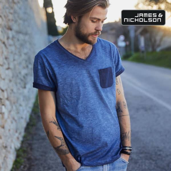 Uomo con barba e tatuaggi sulle braccia che indossa tshirt blu scollo a V con taschino