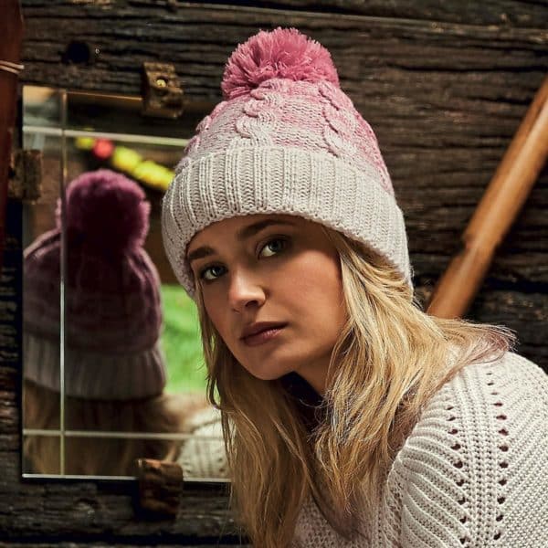 Ragazza con lunghi capelli biondi berretto a maglia con pon pon bianco e rosa specchio sullo sfondo