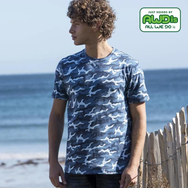 Ragazzo di profilo con cappelli ricci in spiaggia che indossa maglietta camouflage blu
