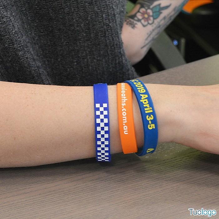 braccio con tre braccialetti con loghi e colori diversi