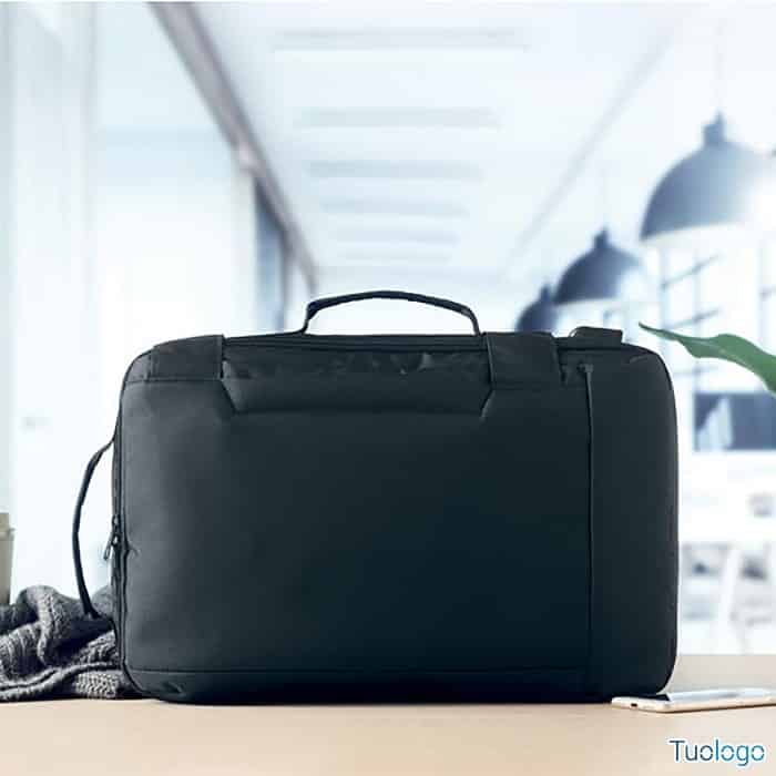 Dettaglio zaino nero di profilo su ripiano con telefono e maglietta