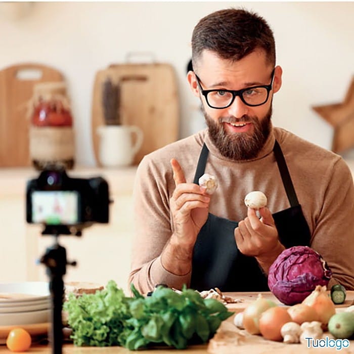 Uomo che si riprende in cucina con addosso grembiule nero