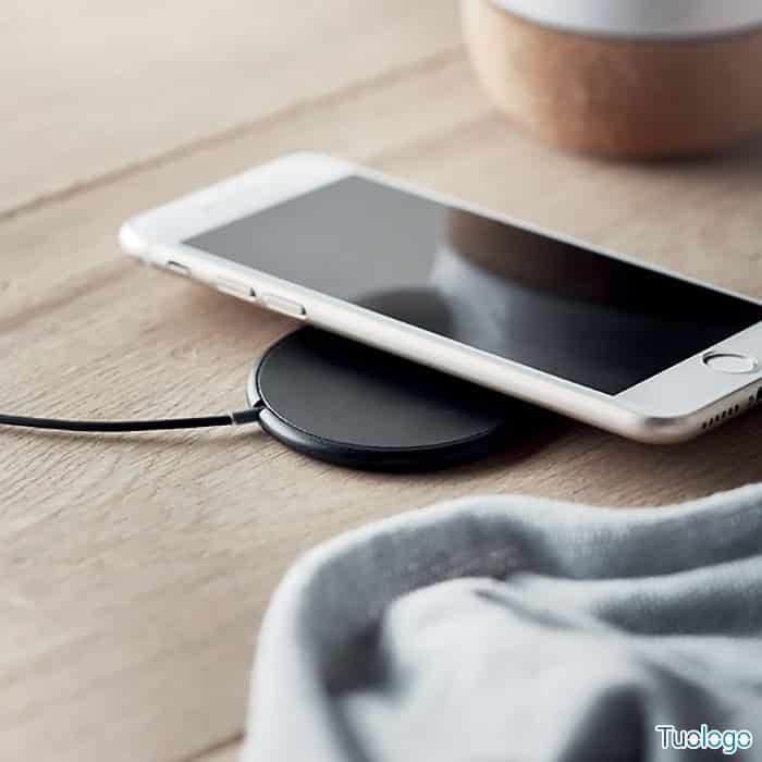 Telefono sopra caricatore tondo nero con presa usb, su tavolo da lavoro