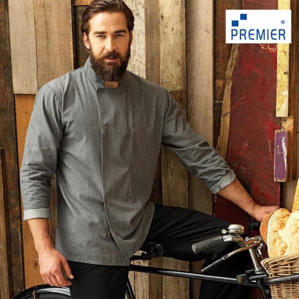 Ragazzo con barbara e giacca da cuoco grigia in bicicletta con cesto di pane contro parete di legno