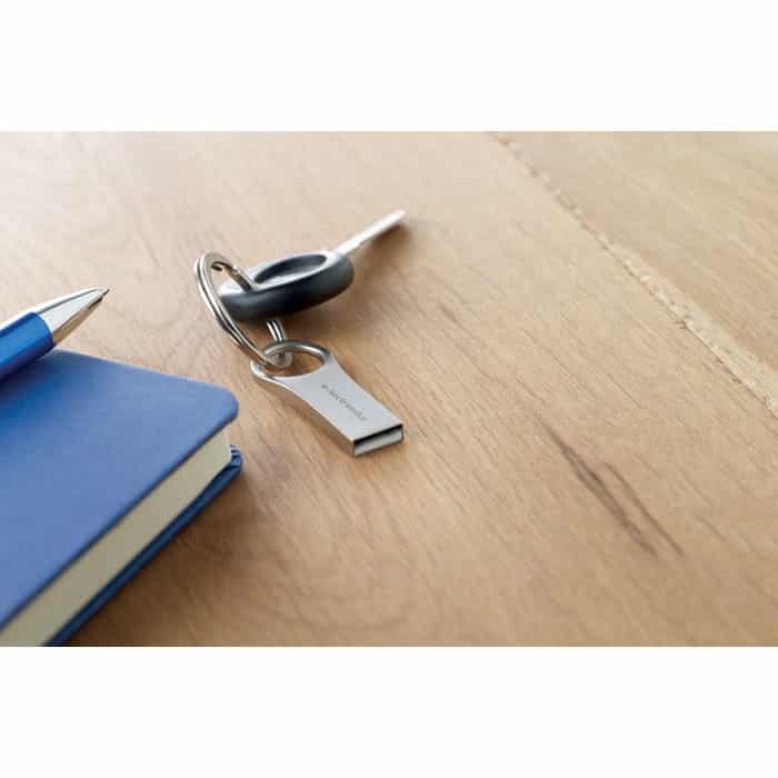 Mini chiavetta usb in alluminio con dettagli rotondi su un tavolo usata come portachiavi