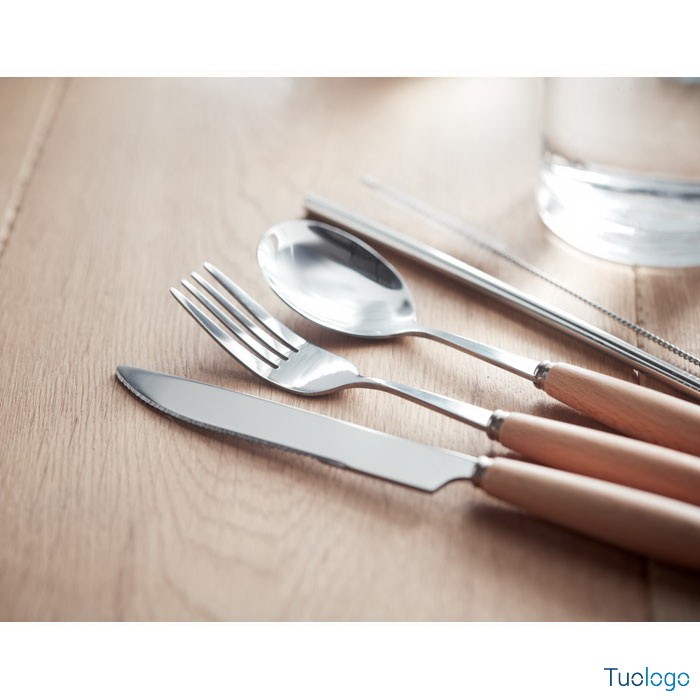 Coltello, forchetta, cucchiaio, cannuccia e spazzola sopra tavolo in legno