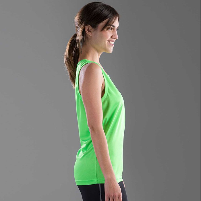 Donna in piedi con canotta verde, su sfondo grigio