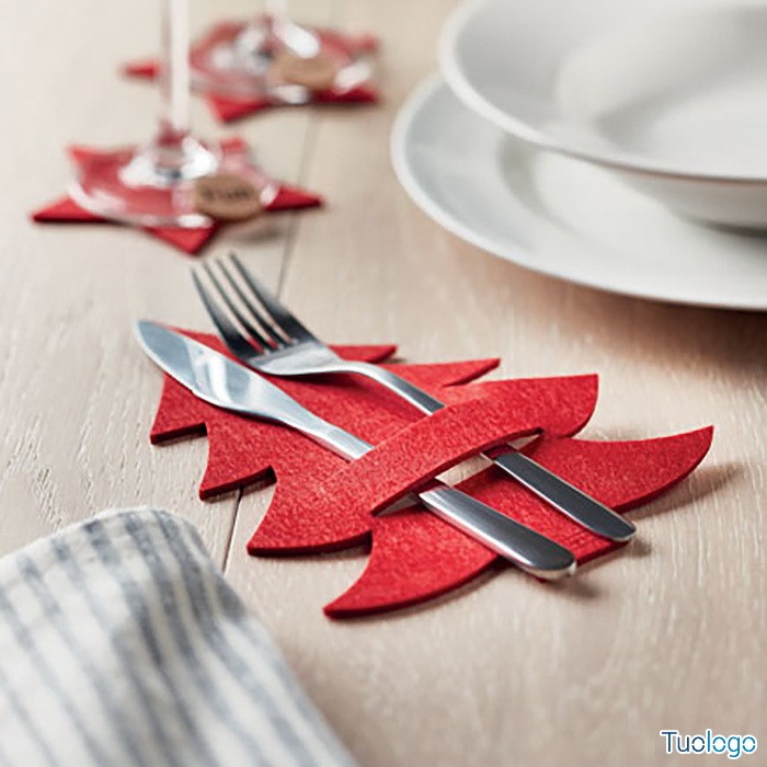 Posate dentro porta posate rosso a forma di albero di natale sopra tavolo di legno