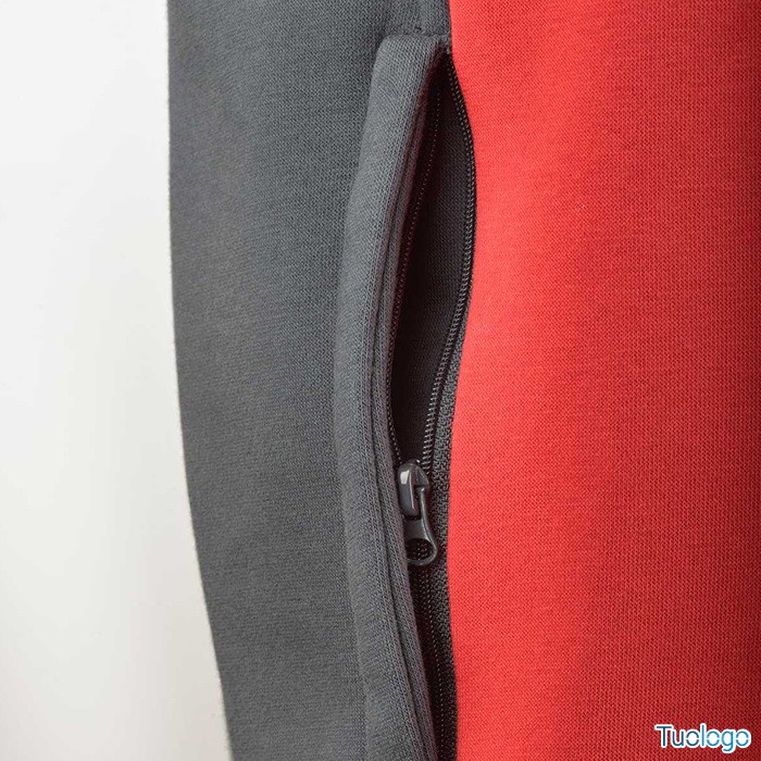 Dettaglio tasca con zip della felpa verde scura e rossa