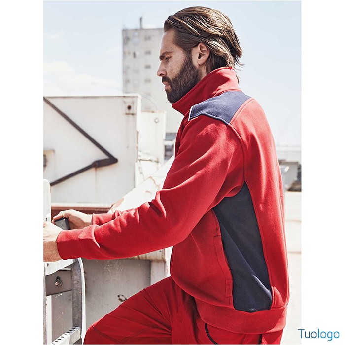 Uomo in piedi di profilo con felpa rossa con inserti neri e pantaloni lunghi rossi